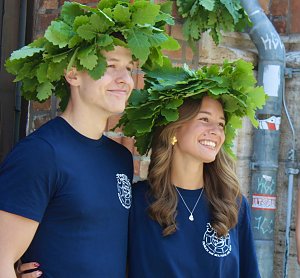 M&auml;dchen und Junge mit Eichenlaubkranz vor der Schule