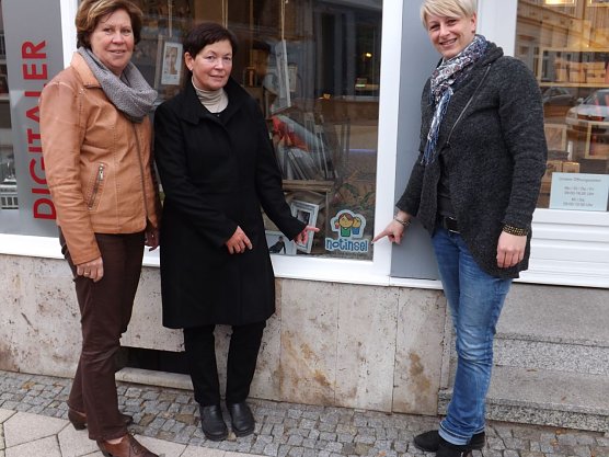 Katja Klaus, Regina Haupt und Birgit Schmidt (v. r.) pr&auml;sentieren das Notinsel-Logo im Schaufenster des Fotogesch&auml;fts am Frauentor in M&uuml;hlhausen.  (Foto: Foto: Mix)