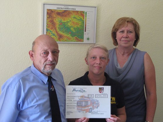 Zur Unterst&uuml;tzung der Kinder- und Jugendarbeit in der Wehr erhielten heute der Brandmeister und Vereinsvorsitzenden J&ouml;rg Rollberg und die Jugendwartin Diana Sch&uuml;tz von Landrat Harald Zanker einen symbolischen Scheck vom Kinderfreundlichen Landkreis in H&ouml;he von 250,00 Euro.  (Foto: Pressestelle Landratsamt Unstrut-Hainich-Kreis)