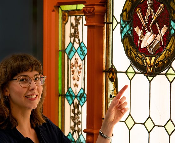 Am kunstvoll gearbeiteten Fenster erkl&auml;rt Sarah P&ouml;nicke die Symbole und deren Bedeutung f&uuml;r die Freimaurer. (Foto: Alexander Hartleib | M&uuml;hlh&auml;user Museen)