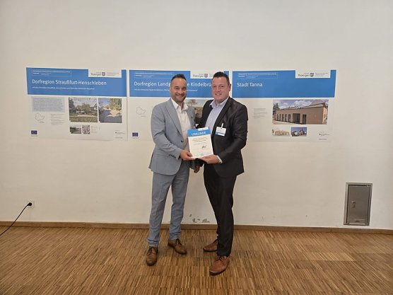 B&uuml;rgermeister Jan Riemann und Christoph Reimann, Fachbereichsleiter f&uuml;r Stadtentwicklung, nahmen die Urkunde f&uuml;r die Dorfregion M&uuml;hlhausen S&uuml;d am 21. August 2025 in Neustadt/Orla entgegen. (Foto: Stadt M&uuml;hlhausen)