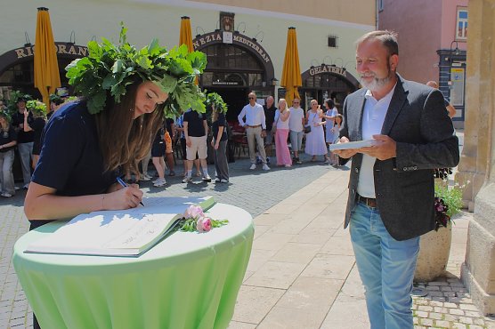 Bild: Abiturientin tr&auml;gt sich in das "Goldene Buch" der Stadt Bad Langensalza ein. B&uuml;rgermeister Matthias Reinz (re.)