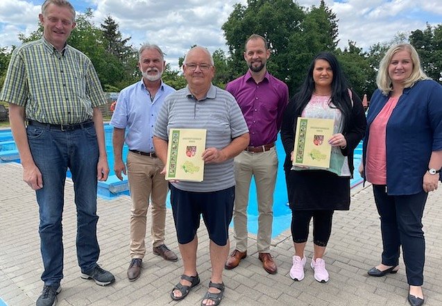 Bild: (v. l.): Carl-Josef Detert (Inhaber Detert Zuchttiere), Landrat Harald Zanker, Michael R&ouml;nsch (Vereinsvorsitzender F&ouml;rderverein Freibad Wiegleben), Mittels&ouml;mmerns B&uuml;rgermeister Thomas Drengenburg, Dorfk&uuml;mmerin Kathleen Kehr und Jane Croll (B&uuml;rgermeisterin Wiegleben) bei der &Uuml;bergabe.