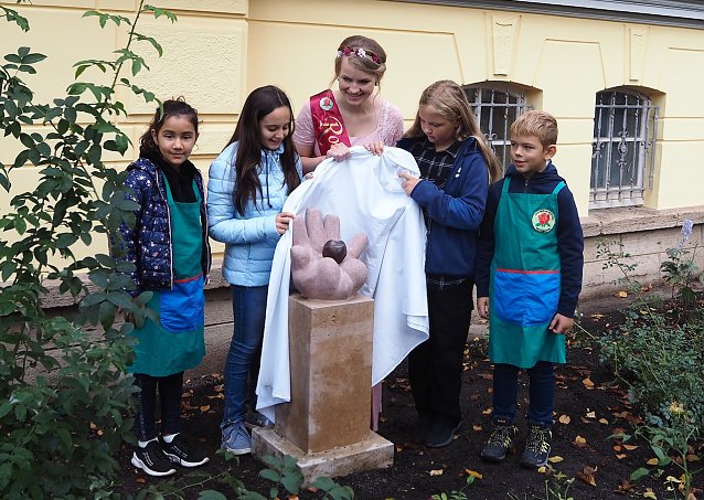 Bild: Die Rosenk&ouml;nigin enth&uuml;llt mit den Kindern die neue Skulptur in ihrem Rosengarten