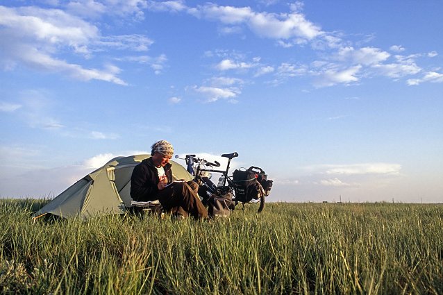Bild: Ein Mann sitzt in der Graslandschaft Kasachstan vor seinem Zelt