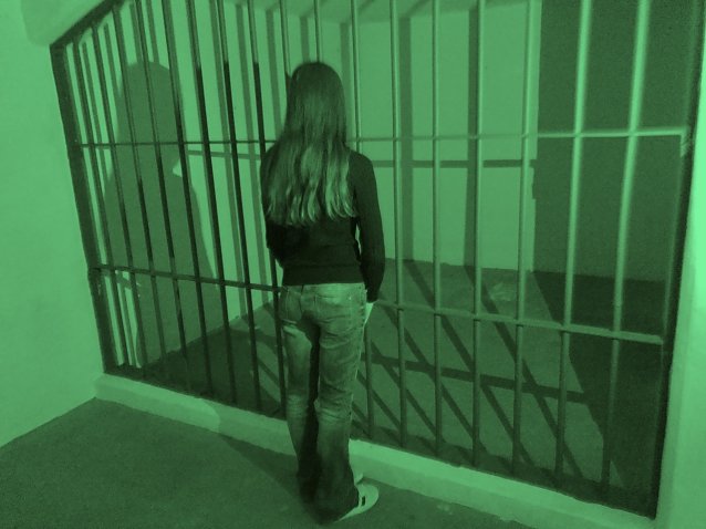 Bild: Frau steht mit dem R&uuml;cken zur Fotografin mit dem Blick zu dem Kellergef&auml;ngnis