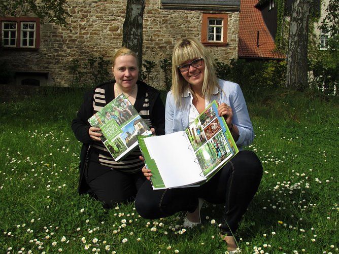 Ute Rust und Gesch&auml;ftsstellenleiterin Anne-Katrin Ibarra Wong (v.l.) pr&auml;sentieren die hochwertige G&auml;steinformationsmappe. (Foto: Foto: Tourismusverband der Welterberegion Wartburg Hainich.)