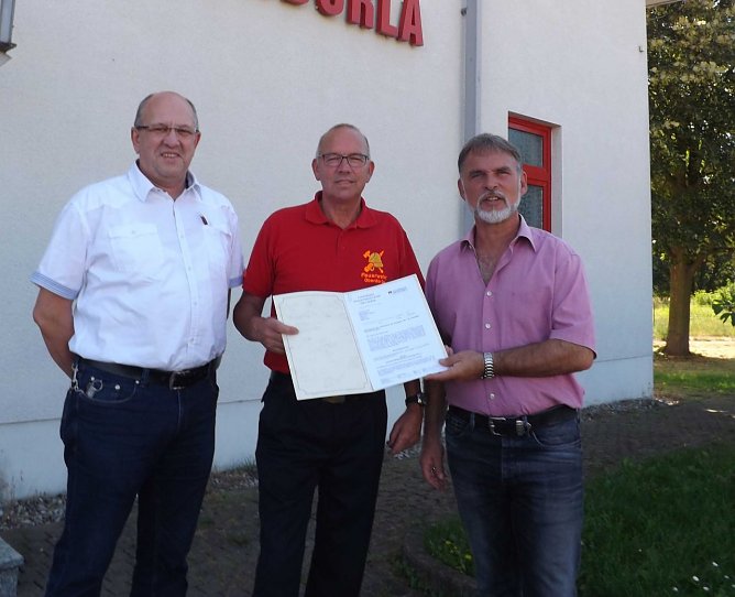B&uuml;rgermeister Winfried B&ouml;tticher und Ger&auml;tewart Bernd Naumann nahmen den Zuwendungsbescheid von Landrat Harald Zanker am Feuerwehrhaus entgegen. (Foto: Pressestelle Landratsamt Unstrut-Hainich-Kreis)