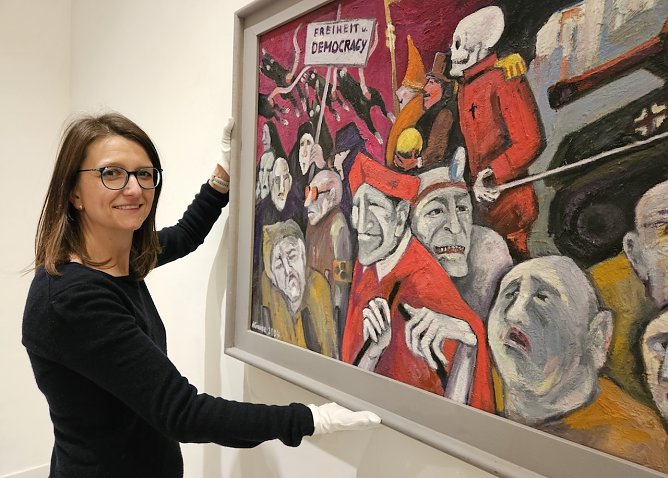 Die Kuratorin Dr. Nora Hilgert mit dem Gem&auml;lde Der anachronistische Zug oder �Freiheit und Democracy� (Foto: Matthias Nolte M&uuml;hlh&auml;user Museen)
