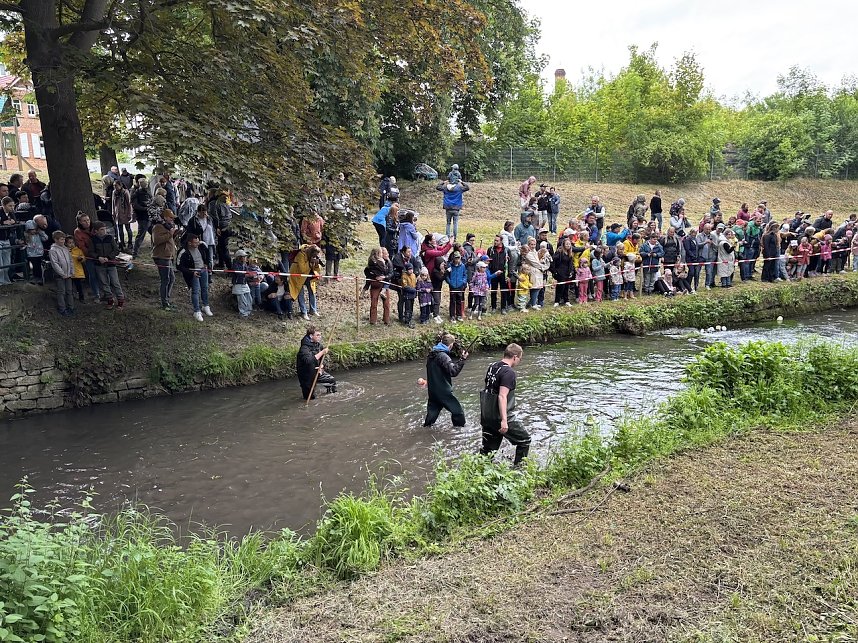 Menschen und Enten am und im Wasser